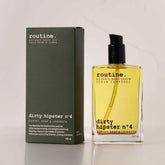 routine Dirty Hipster n°4 Botanic Body Oil in 100ml glass bottle with black pump dispenser next to olive green cardboard packaging box showing earthy scent description