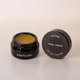 Routine Sexy Sadie botanic perfume balm - open black glass jar showing golden-yellow solid perfume with dark grey lid displaying product name