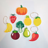 Pop-Up Sponges - Collection of flat, compressed cellulose sponges in fruit and vegetable shapes including pumpkin, strawberry, pineapple, lemon, banana, bok choy, mangosteen, pear, and chili pepper, each with a hanging loop