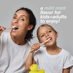Woman and child brushing their teeth together with a yellow rubber duck, promoting a mild mint flavor.