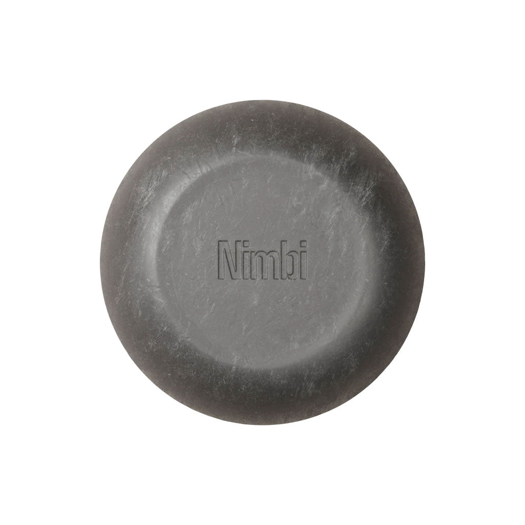Nimbi Shave Foam Puck in charcoal next to its white paper carton showing 0.5% activated charcoal and organic shea butter ingredients