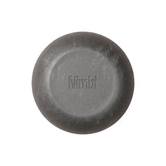 Nimbi Shave Foam Puck in charcoal next to its white paper carton showing 0.5% activated charcoal and organic shea butter ingredients