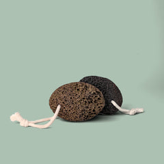 Two pumice stones with white strings on a light green background