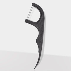 Close-up of The Humble Co. black dental floss pick displaying ergonomic curved handle with textured grip pattern and brand name embossed on side for secure handling