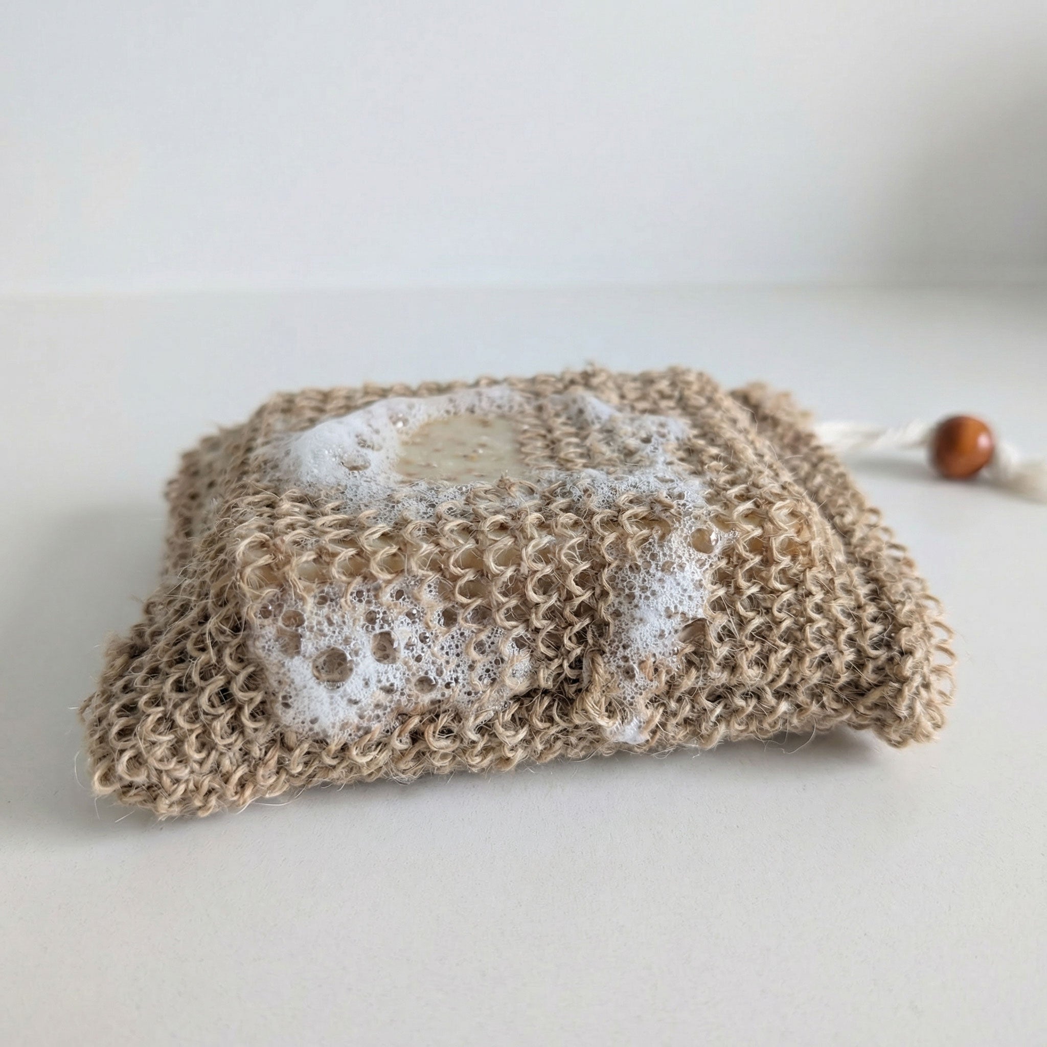 Hemp soap bag with lathered bar soap showing exfoliating texture and foam creation