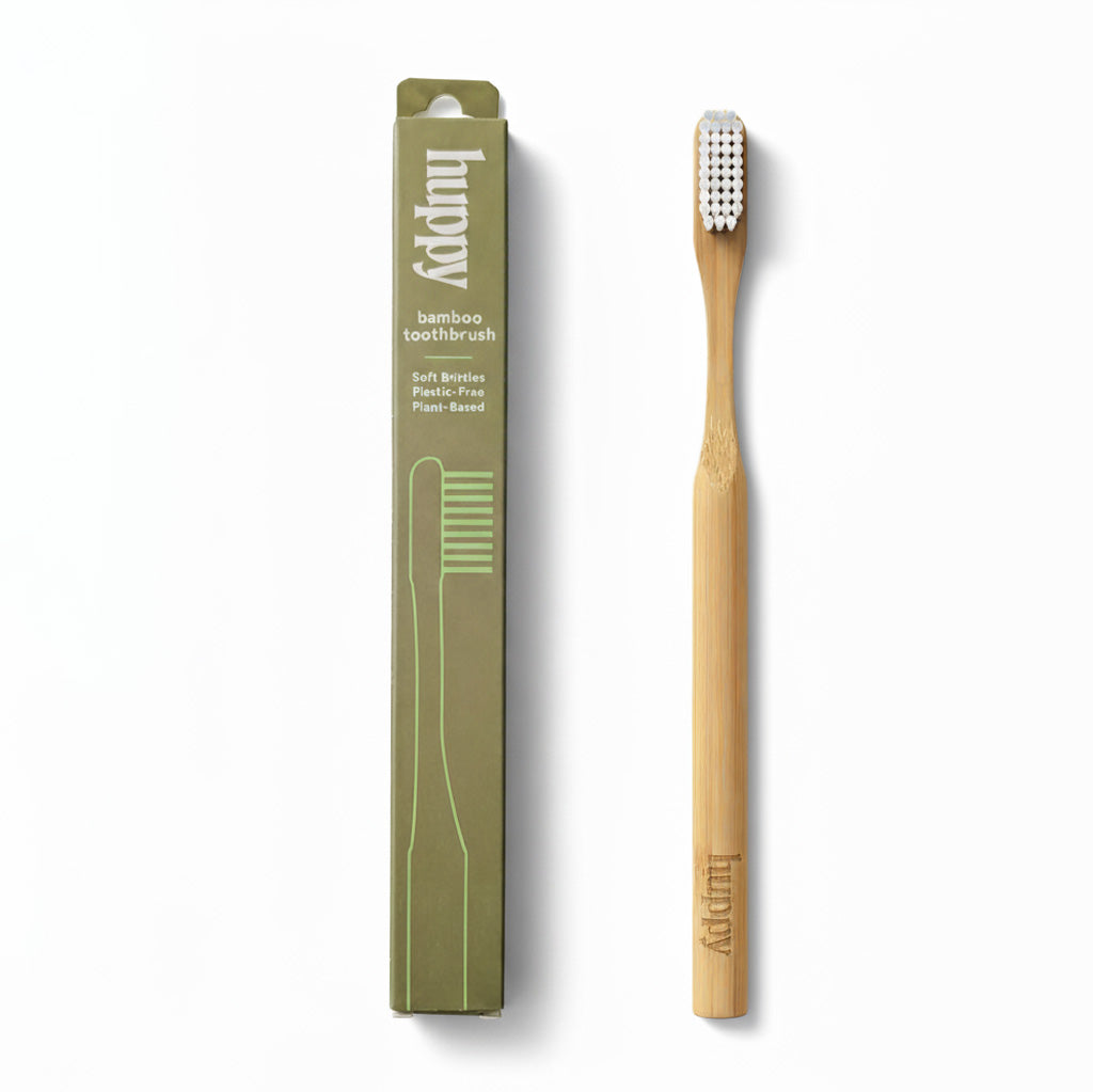 huppy bamboo toothbrush with eco-friendly olive green cardboard packaging showing soft bristles, plastic-free, and plant-based features alongside natural bamboo toothbrush with white bristles