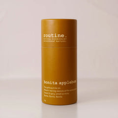 Routine Bonita Applebom deodorant in a mustard-yellow cylindrical paper tube with white “bonita applebom” branding, standing on a beige surface against a matching beige backdrop.