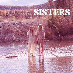 Moon Sisters brand imagery - two women in bohemian dresses standing by water with mountain landscape - representing natural, feminine lifestyle and floral deodorant inspiration