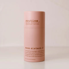 Routine Moon Sisters deodorant stick in blush‑pink paper tube with brown “moon sisters” branding, standing on a beige surface against a matching beige backdrop.