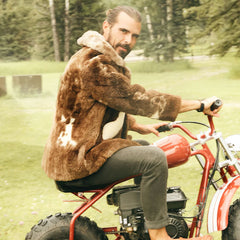 Bearded man in brown fur coat on motorcycle representing the rugged, sophisticated aesthetic of Routine Reuben & The Desert deodorant's target audience