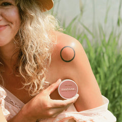 routine Sexy Sadie natural deodorant - blonde woman in white lace top holding coral pink deodorant jar outdoors - lifestyle shot showing 58g vegan aluminum-free deodorant for natural beauty routine
