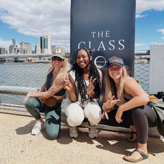Three women posing outdoors with The Class deodorant promotional banner - lifestyle image showing diverse users of luxury natural deodorant for active lifestyles
