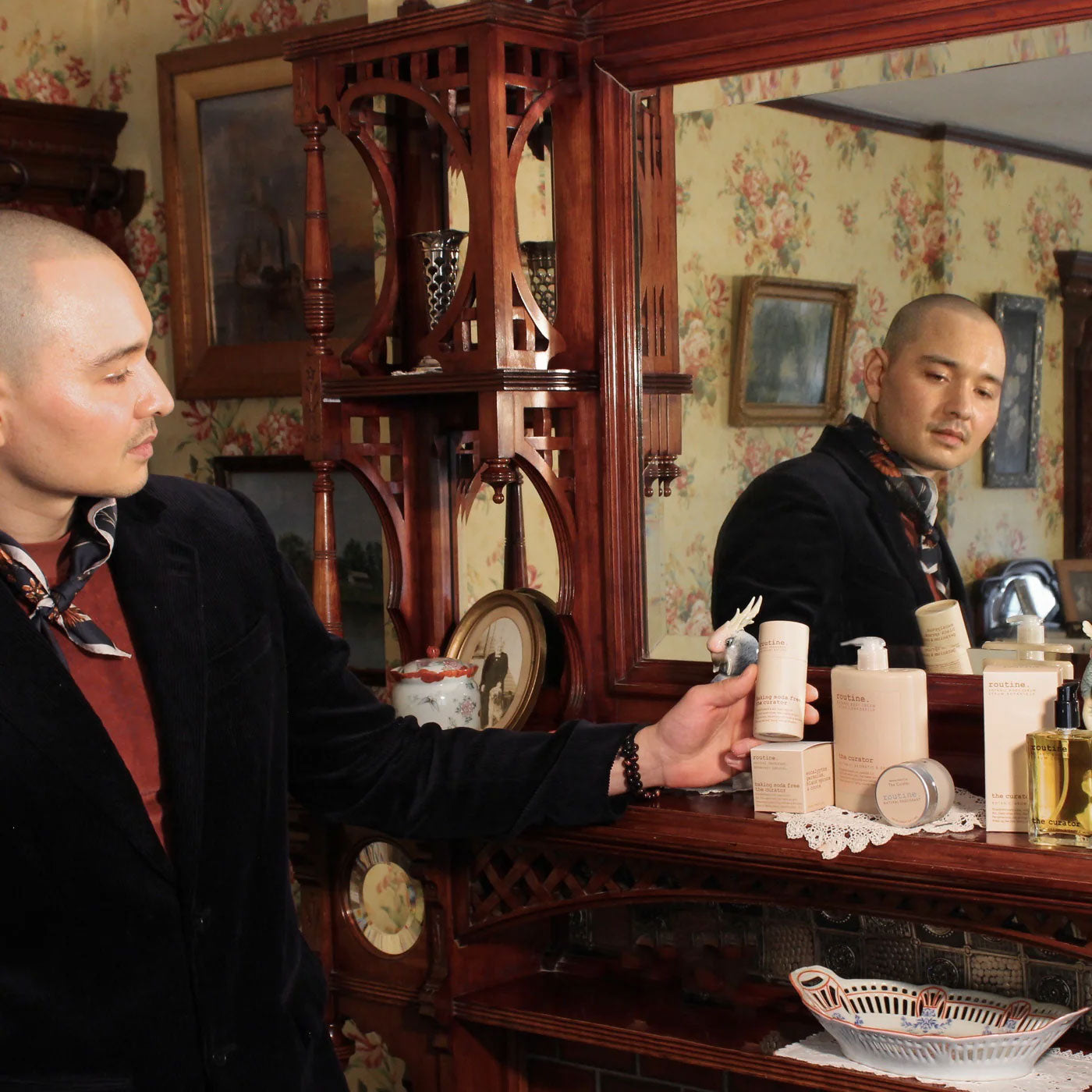A man holding The Curator deodorant stick in a vintage bedroom setting showing sustainable paper packaging.