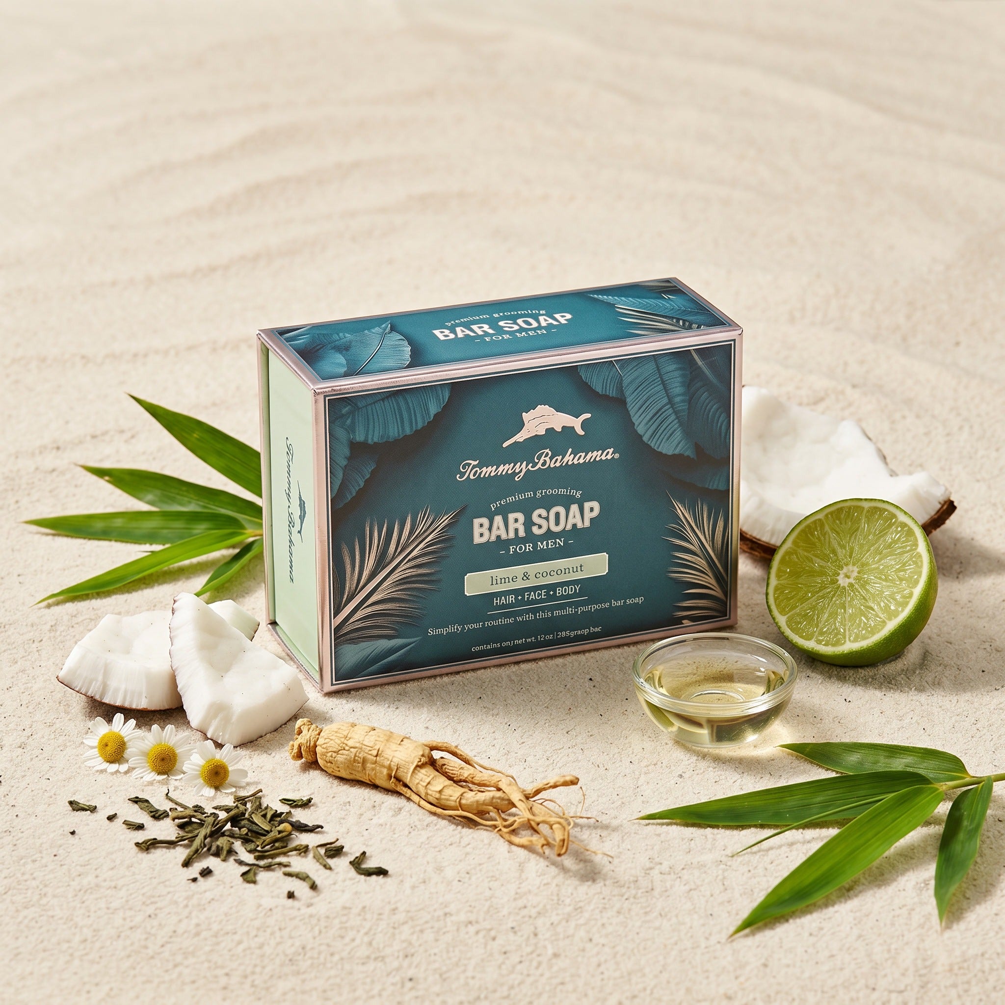 Tommy Bahama Lime & Coconut Bar Soap box arranged on white sand with key ingredient props including fresh lime, coconut chunks, ginseng root, chamomile flowers, green tea leaves, and bamboo leaves